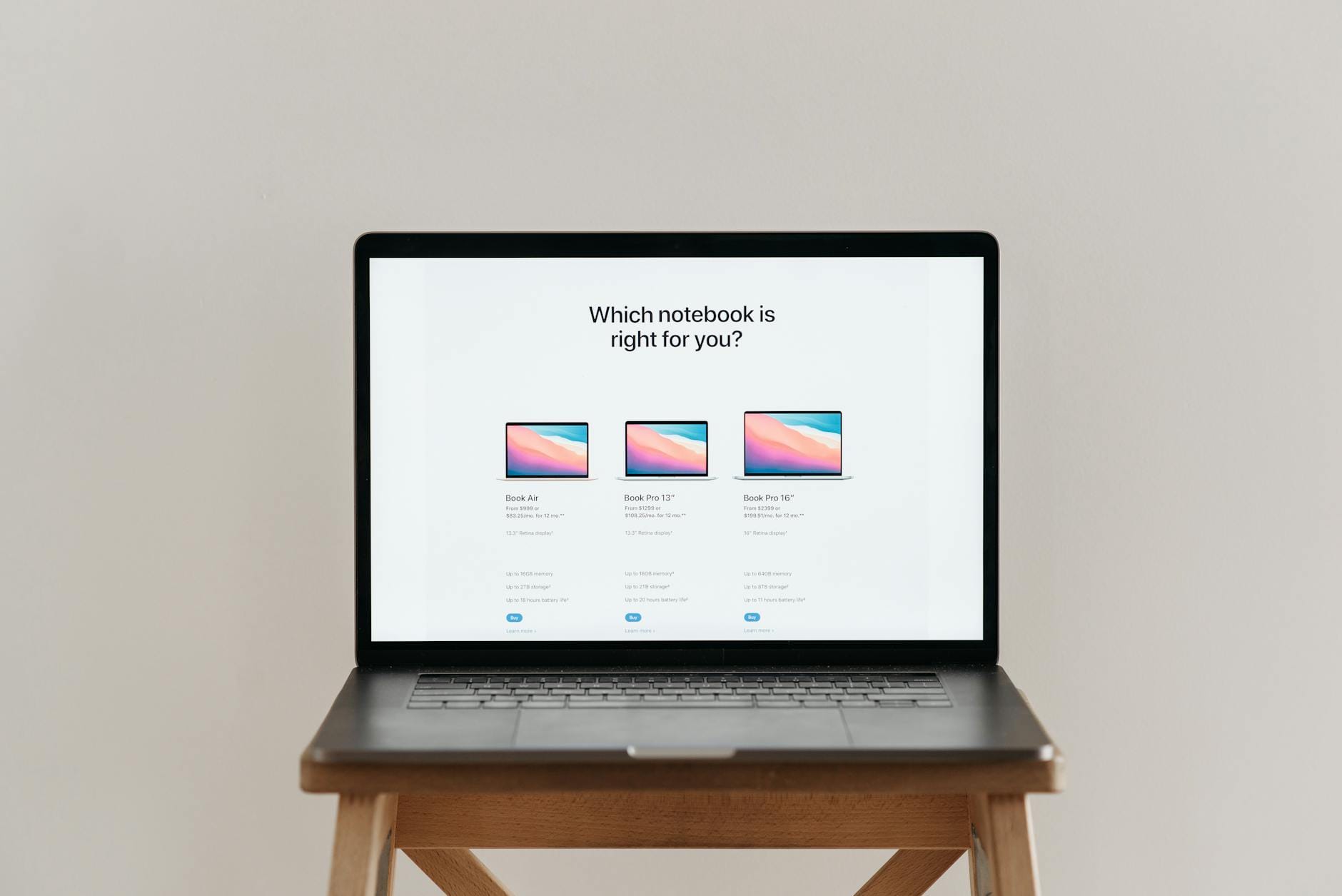 Otwarty laptop na drewnianym stołku z tabelą porównania notebooków