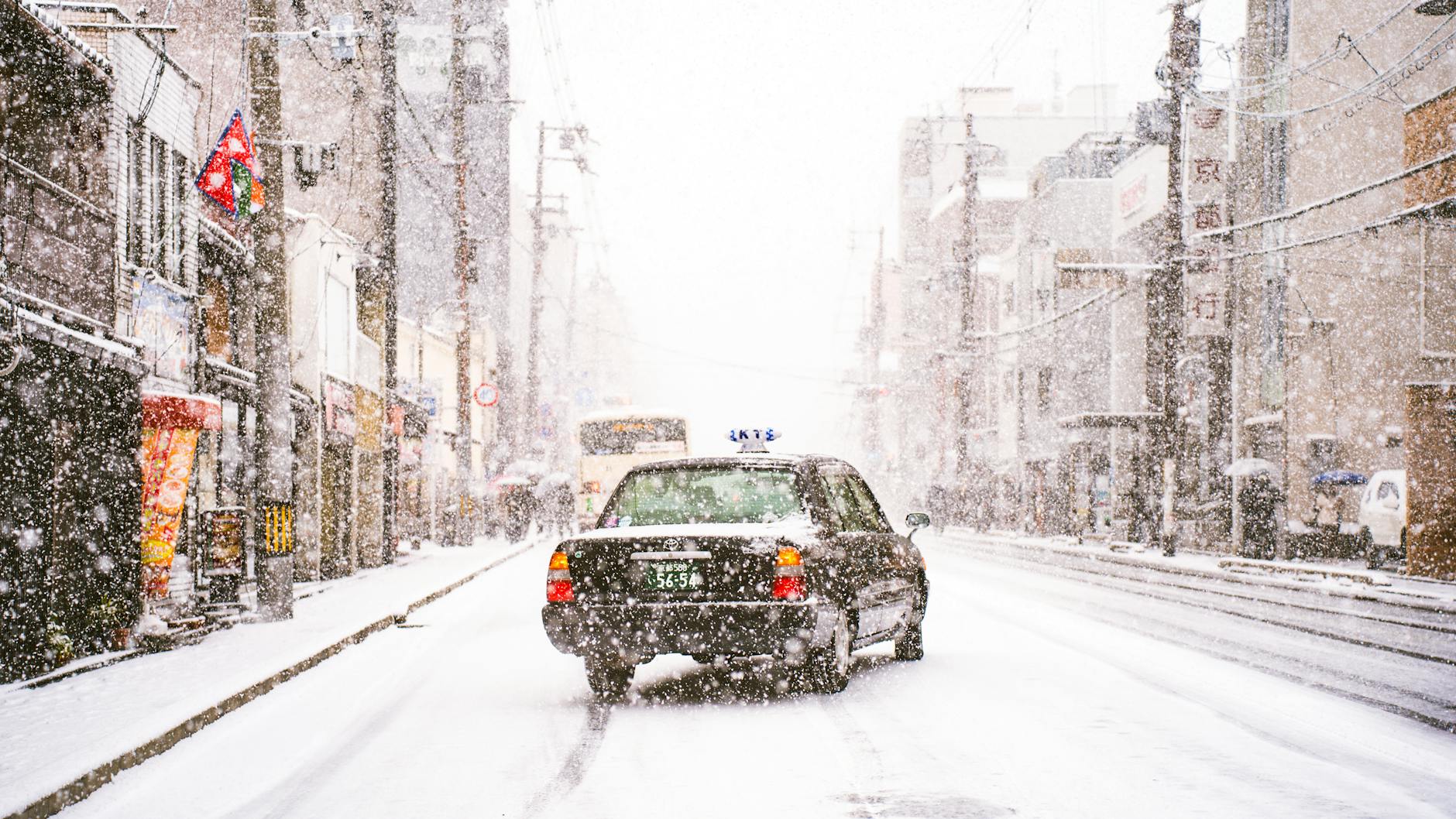 Taxi jedzie ośnieżoną ulicą w zimowym centrum miasta