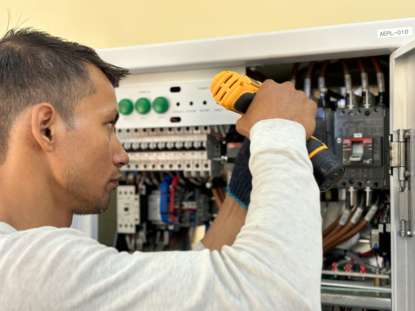 Elektryk montujący wyłącznik w domowej rozdzielnicy elektrycznej