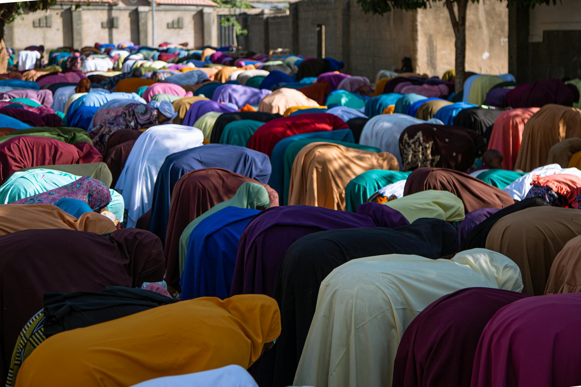 Ludzie modlący się na zewnątrz w trakcie islamskiej modlitwy