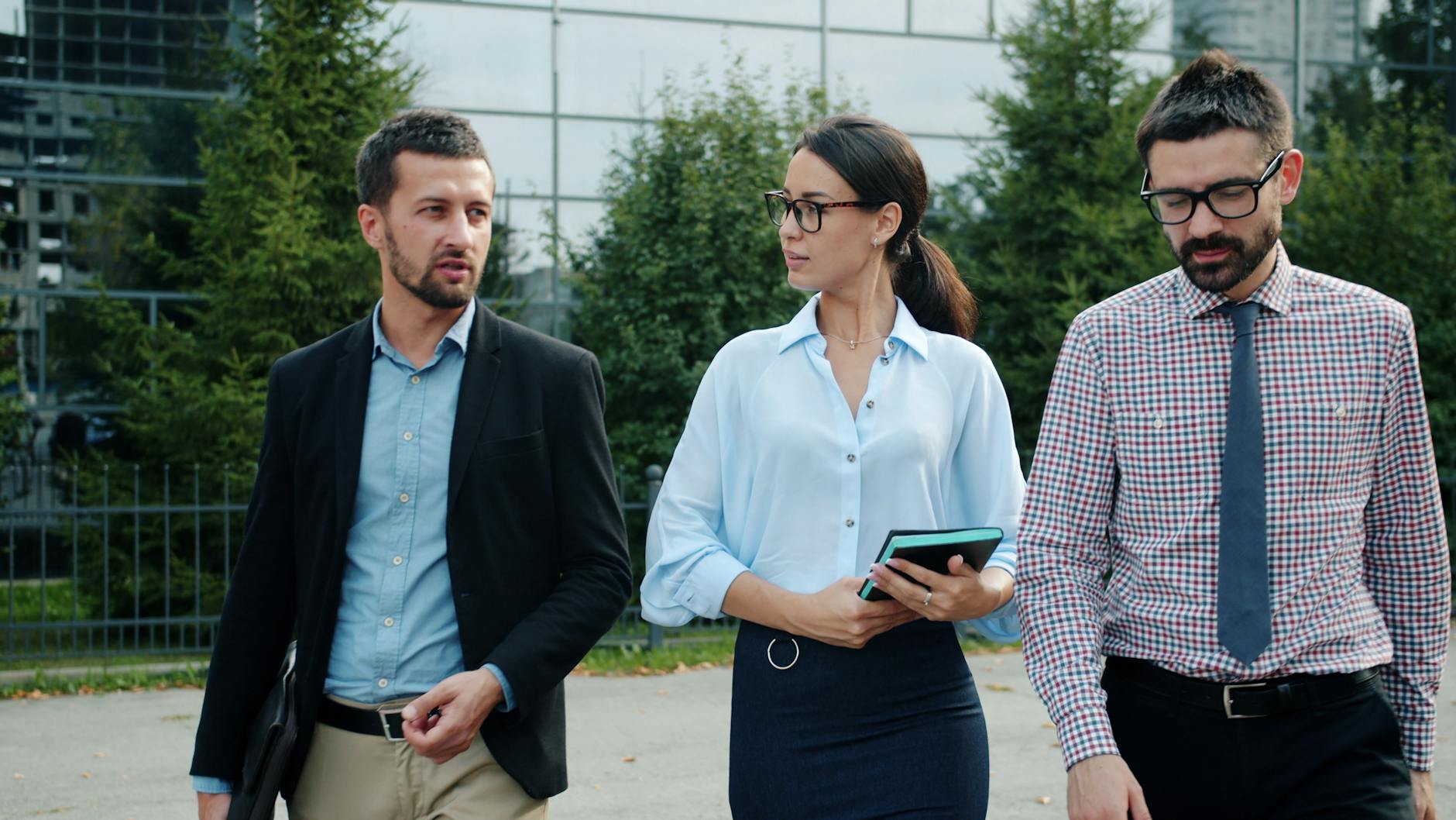 Trzech biznesmenów omawia wdrożenie 5G w nowoczesnej przestrzeni miejskiej