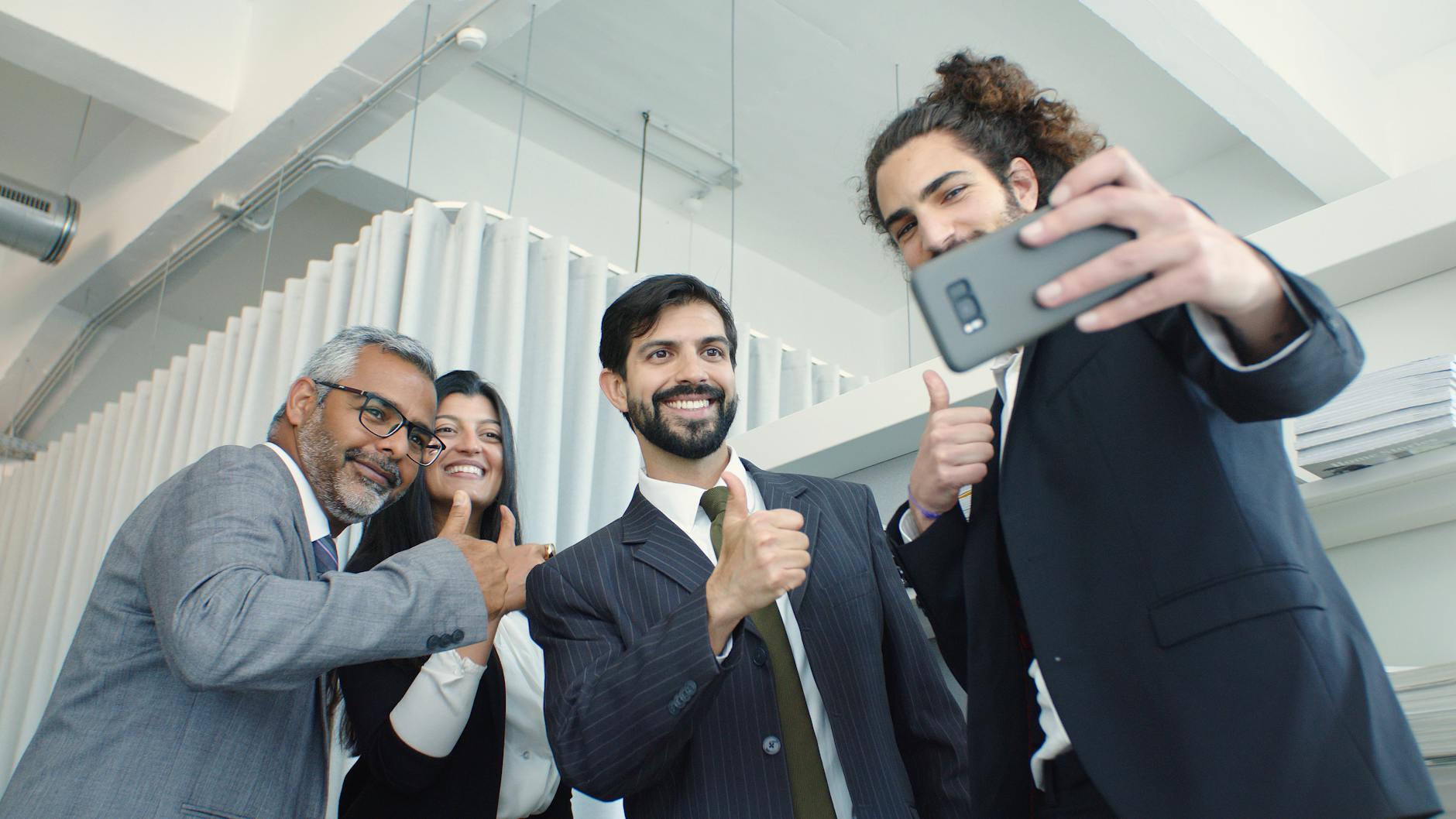 Uśmiechnięci współpracownicy biurowi robią razem selfie